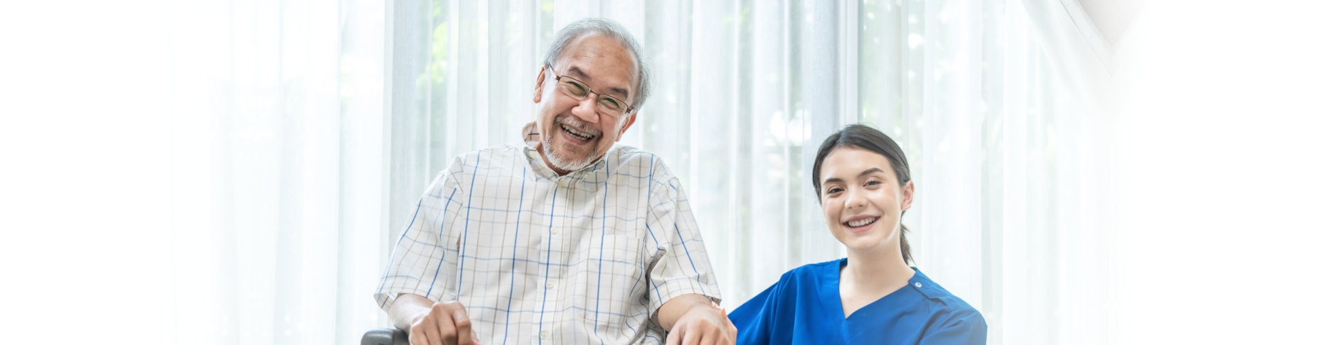 caregiver and patient in a wheelchair smile on the camera